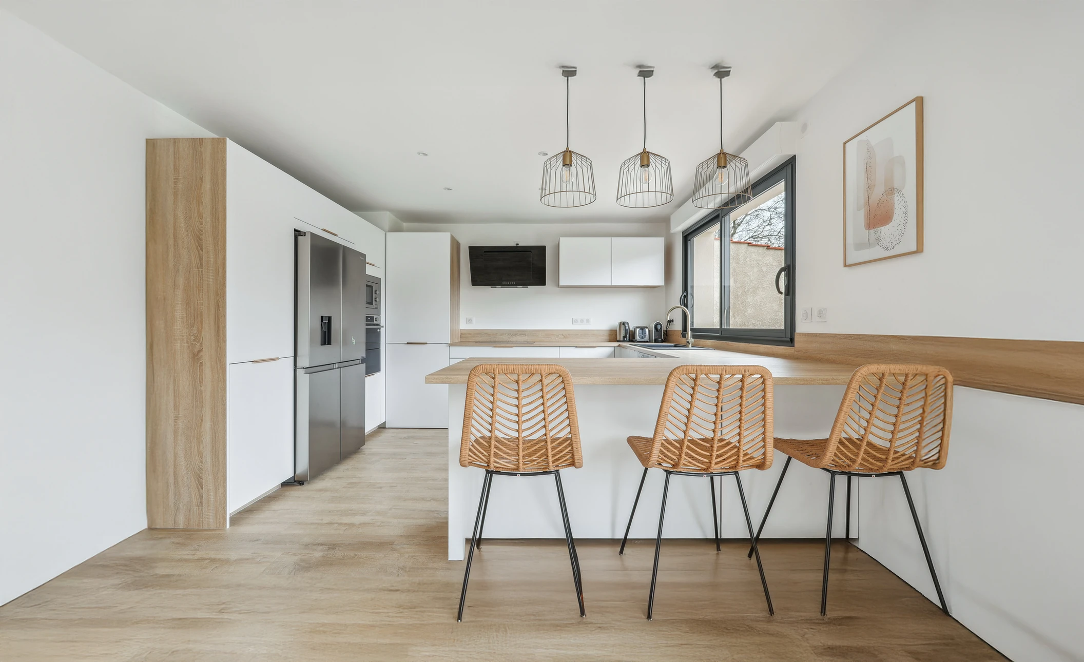 Cuisine moderne ouverte avec îlot central et trois tabourets en rotin