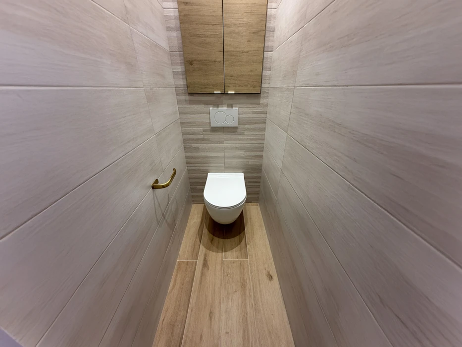 Pièce vide récemment rénovée avec parquet en chêne massif, murs peints en beige clair, plafond avec moulures