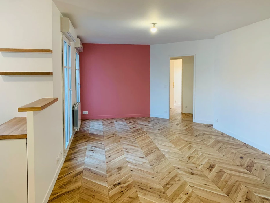 Intérieur d'appartement rénové avec salon lumineux aux murs blanc et rouge bordeaux