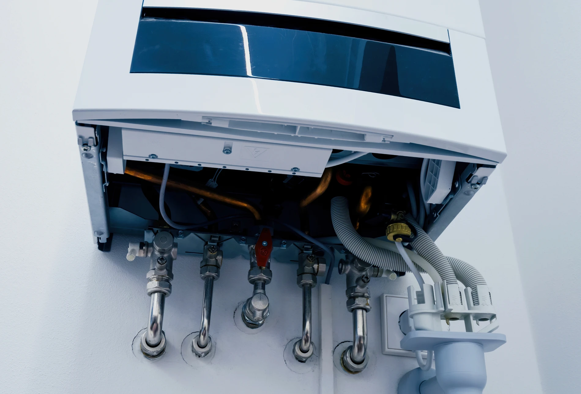 Plombier en uniforme bleu installant un radiateur à ailettes blanches dans une maison en construction